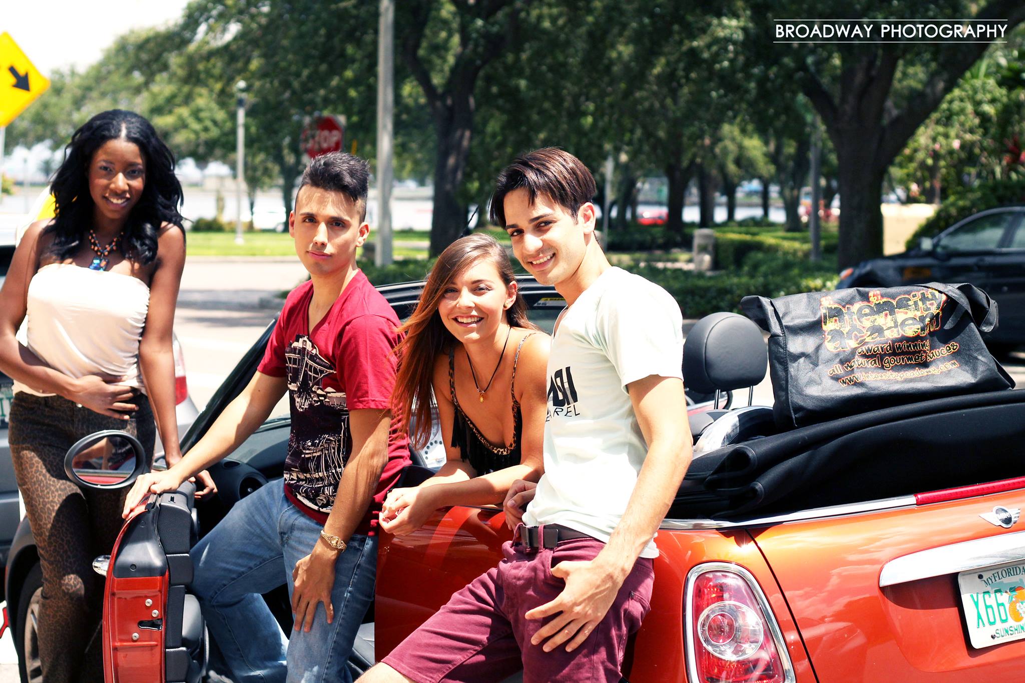 Photo of 4 teens posing next to a red convertible Mini Cooper