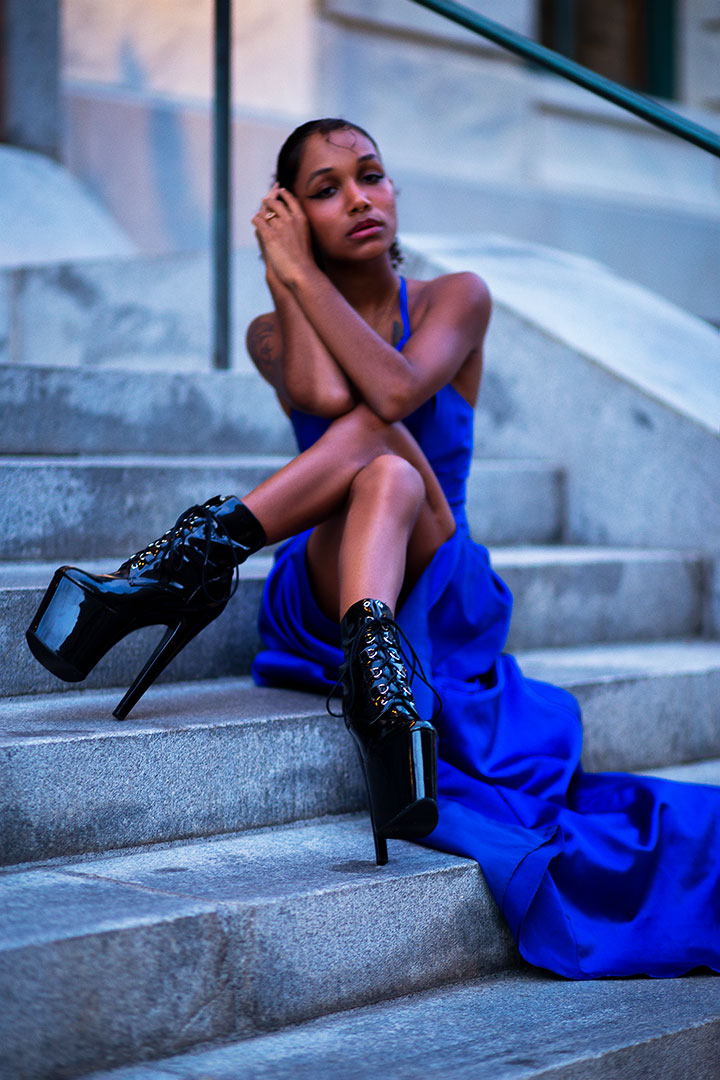 Lady in long vivid blue dress sitting on staircase